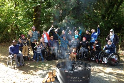 Oregon SCI campers group of Oregon SCI members posing for a photo next to campfire